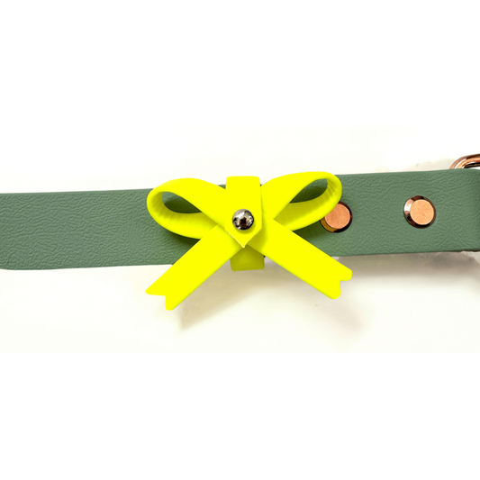 Die StallSchätze Gelbe Schleife für Hunde ist ein grünes Lederhalsband mit einer gelben Schleife, einem silbernen Niet in der Mitte und kupfernen Nieten an der Seite.