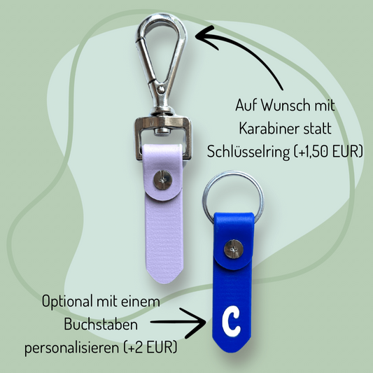 Abgebildet sind zwei *NEU* Gramm-Anhänger Beschriftung für Winterdecken von StallSchätze: einer (hellviolett) mit silbernem Karabiner, und einer (blau mit weißem C) mit Schlüsselring. Der deutsche Text beschreibt den optionalen Karabiner, das Biothane und die StallSchatz-Personalisierung.