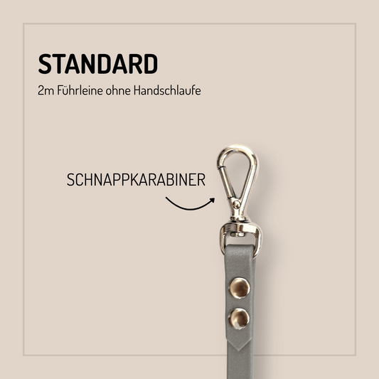 Eine graue StallSchätze Biothane-Hundeleine 2m, individuell konfigurierbar, mit Metallnieten und Karabinerhaken ist senkrecht dargestellt. Der Text lautet STANDARD, 2m Führleine ohne Handschlaufe, SCHNAPPKARABINER mit einem Pfeil auf den Karabinerhaken.