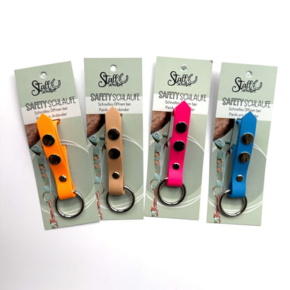Vier StallSchätze Safety-Schlaufe für Halfter Schlüsselanhänger in Gelb, Hellbraun, Rosa und Blau - jeweils mit Produktkarte und Metallring - stehen nebeneinander auf weißem Grund, perfekt für Pferdefans.