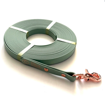 Die StallSchätze Biothane-Longe 8 Meter ist eine gewickelte, hellgrüne Hundeleine mit roségoldener Metallschließe und Nieten. Ihr modernes Design mit zwei hellgrünen Bändern macht sie pflegeleicht für tägliche Spaziergänge.