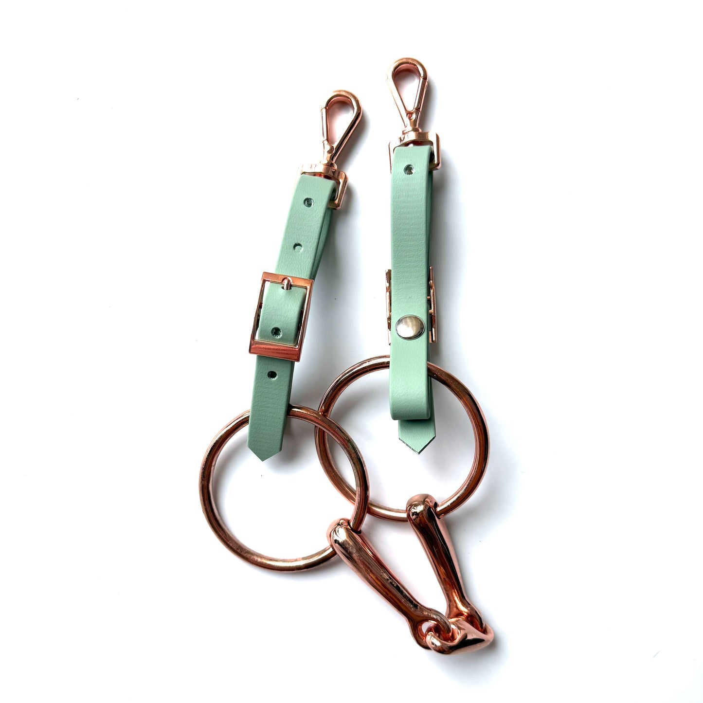 Zwei mintgrüne StallSchätze Edle Biothane-Bithanger mit goldenen Schnallen, Verschlüssen und großen Ringen sind auf weißem Hintergrund abgebildet; ein Ring ist zusätzlich mit einem goldenen Karabinerhaken versehen.