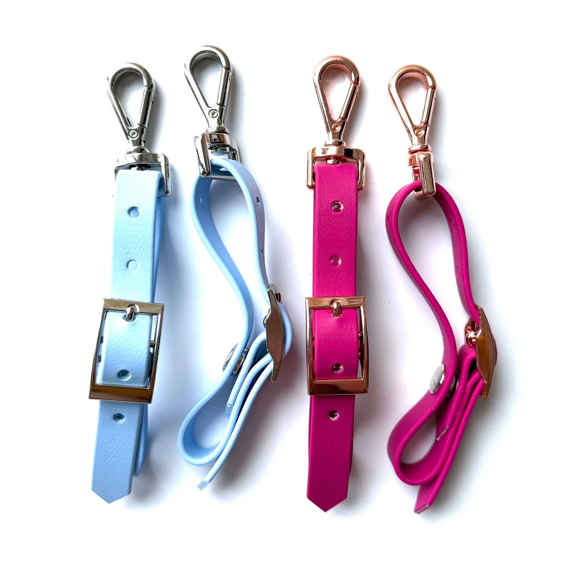 Vier StallSchätze Edle Biothane-Bithanger mit Schnappkarabiner - zwei in hellblau mit silbernen Beschlägen und zwei in rosa mit goldenen Beschlägen - stehen nebeneinander auf weißem Hintergrund.